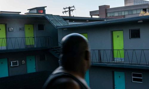 Man looks at thermometer reading 116 degrees outside his apt. building.