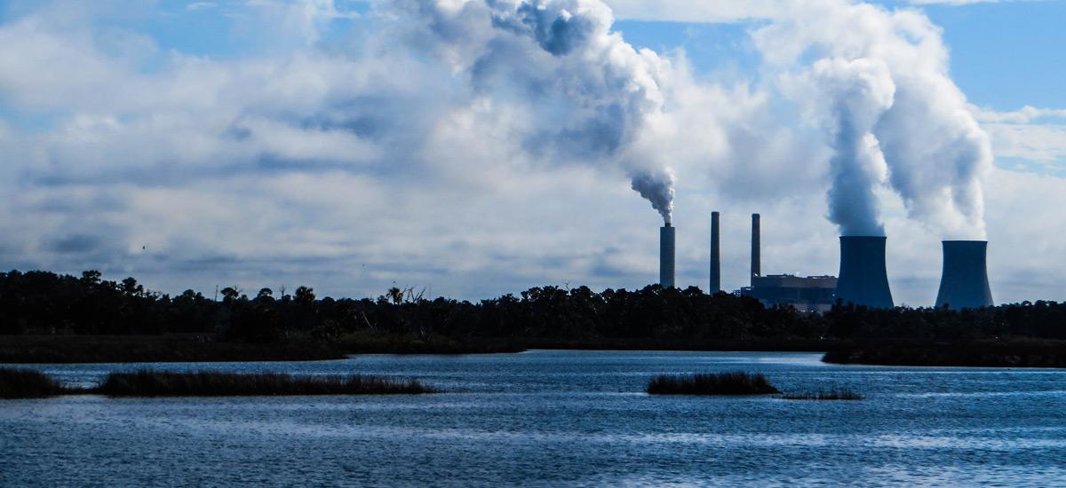 A skyline with power plants emitting smoke.