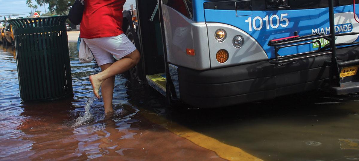 Woman boarding bus in flooded street in Miami, Florida