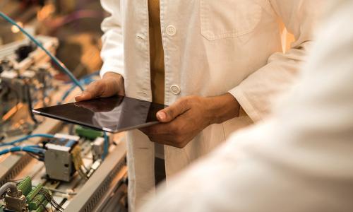 Person in lab coat holding tablet in lab