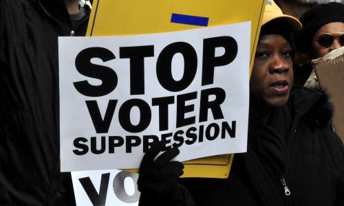 Woman holding 'Stop Voter Suppression' sign at voting rights march