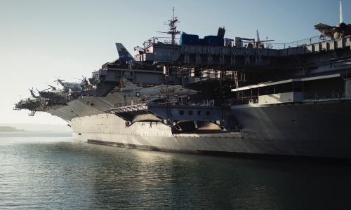 A large NAVY warship sits on a body of water