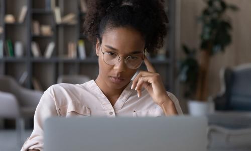 young woman looking thoughtfully at computer screen