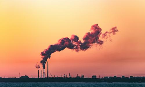 A factory emitting smoke during sunset. 