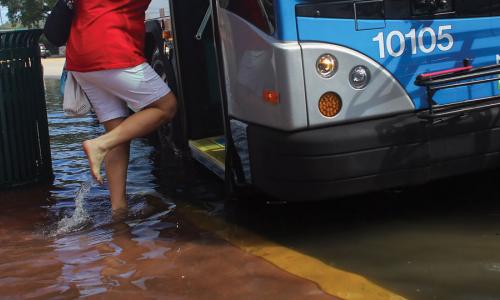 Woman boarding bus in flooded street in Miami, Florida